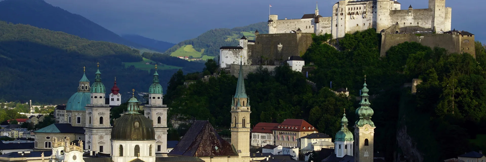 黄昏时分，Hohensalzburg Fortress的白色城墙矗立于萨尔茨堡老城穹顶与屋顶之上，全城皆可望见