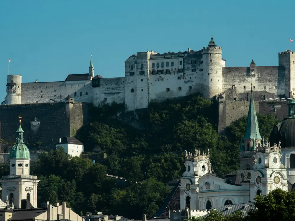 The white walls and towers of Hohensalzburg Fortress on the wooded Festungsberg, Salzburg